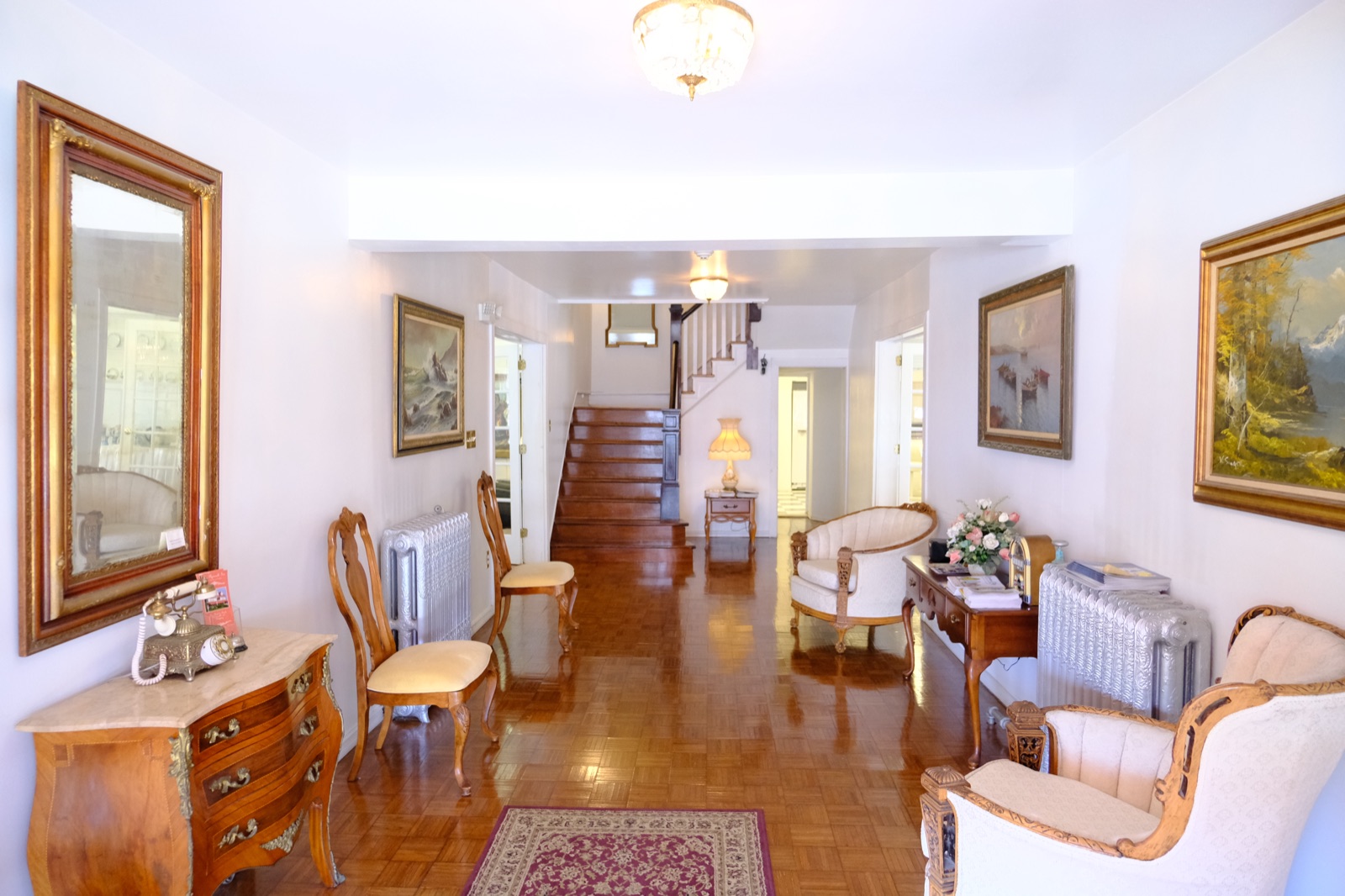The Plymouth Inn's grand foyer with a sweeping staircase, gilt mirror, antique furniture and oil paintings