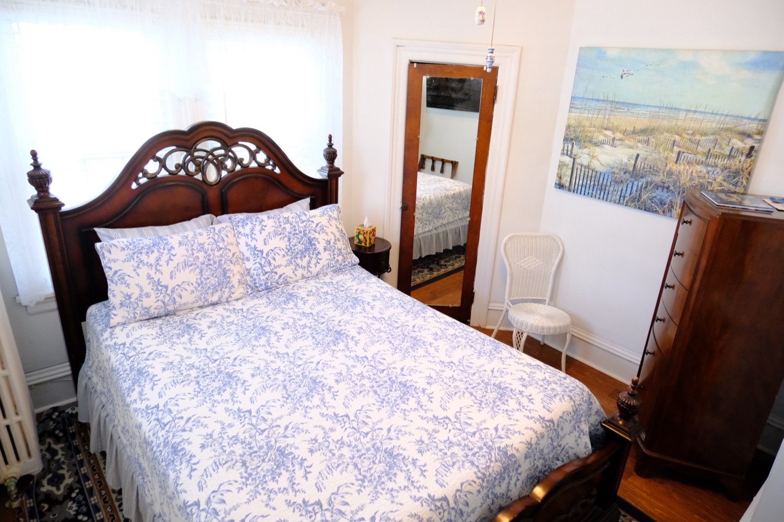 Queen Mum's Suite 1 with a carved wood bed in blue toile linens, floor mirror and a beach painting