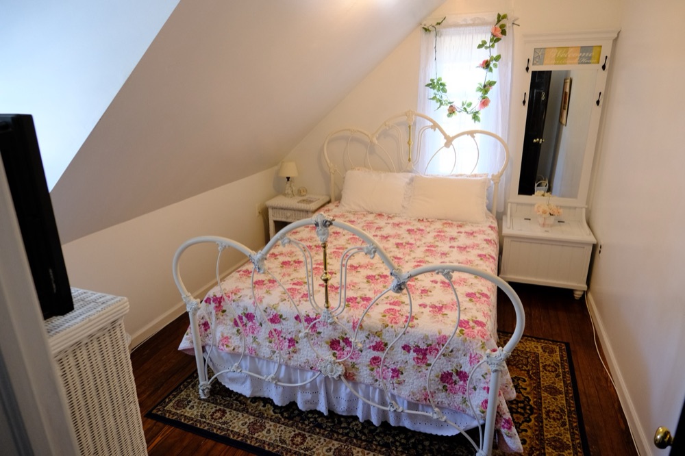 Cozy dormer room with a white iron bed and pink florals